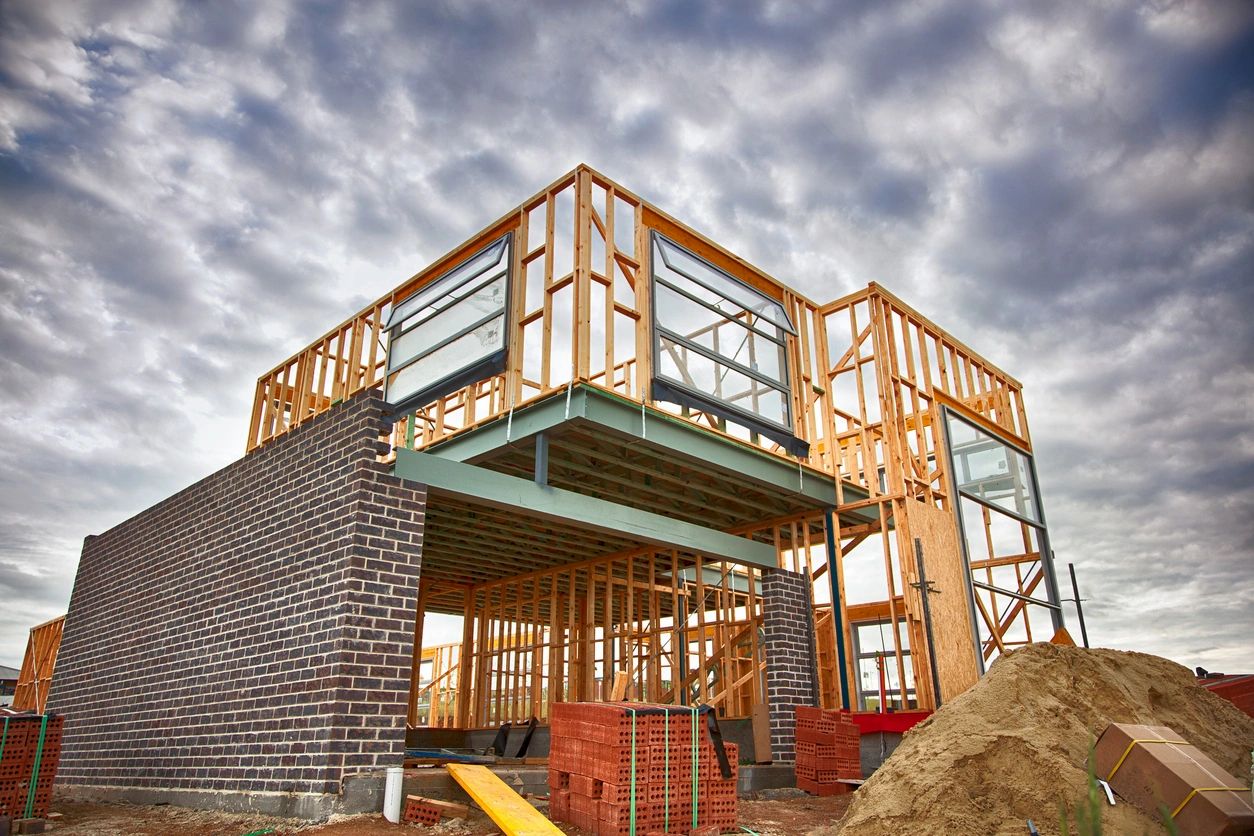 Partially constructed modern house with timber framing under a cloudy sky
