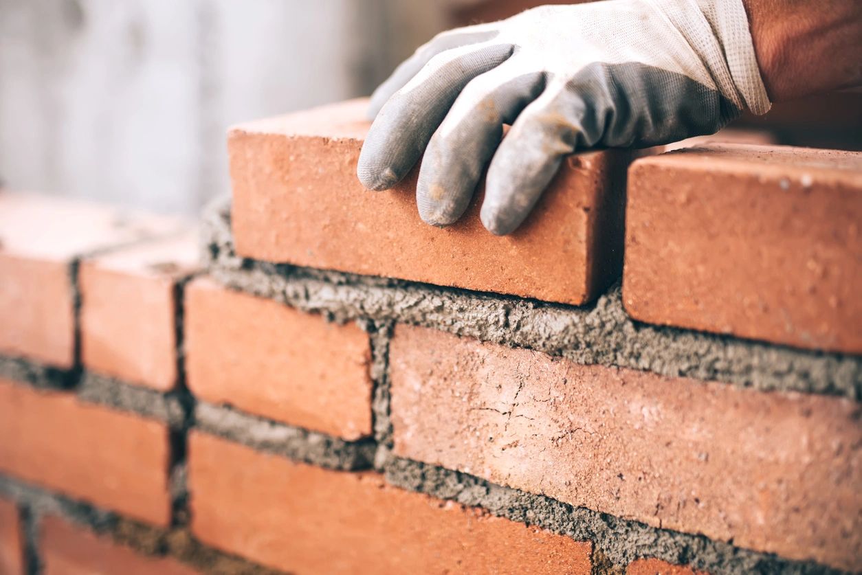 Construction worker placing a red brick with a gloved hand