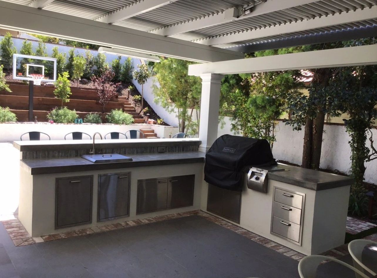 Outdoor kitchen with covered patio and basketball area